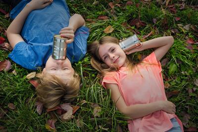 boy and girl with tin phone, fall, autumn, fun, communication, childhood, nature, siblings, friendship, lying down, meadow
