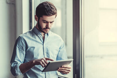 Young businessman using tablet, standing near the window