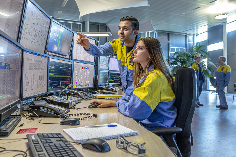 Two process engineering students looking at multiple computer monitors