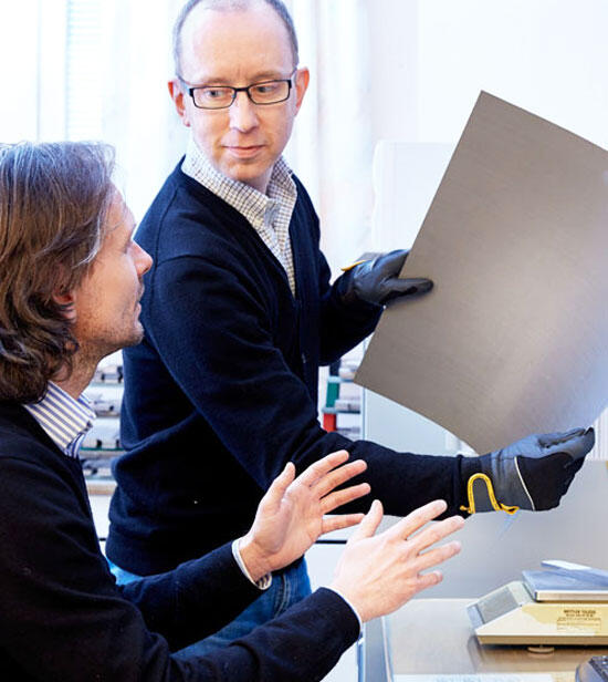 Two men, one holding a panel, having a discussion