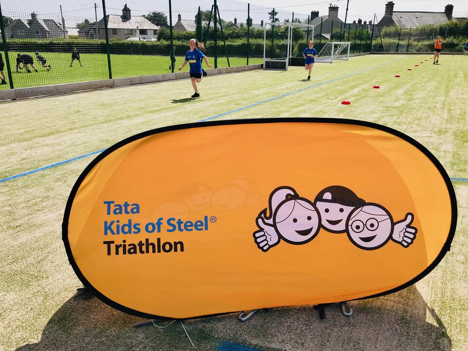 Kids of Steel triathlon banner in foreground and kids warming up in background