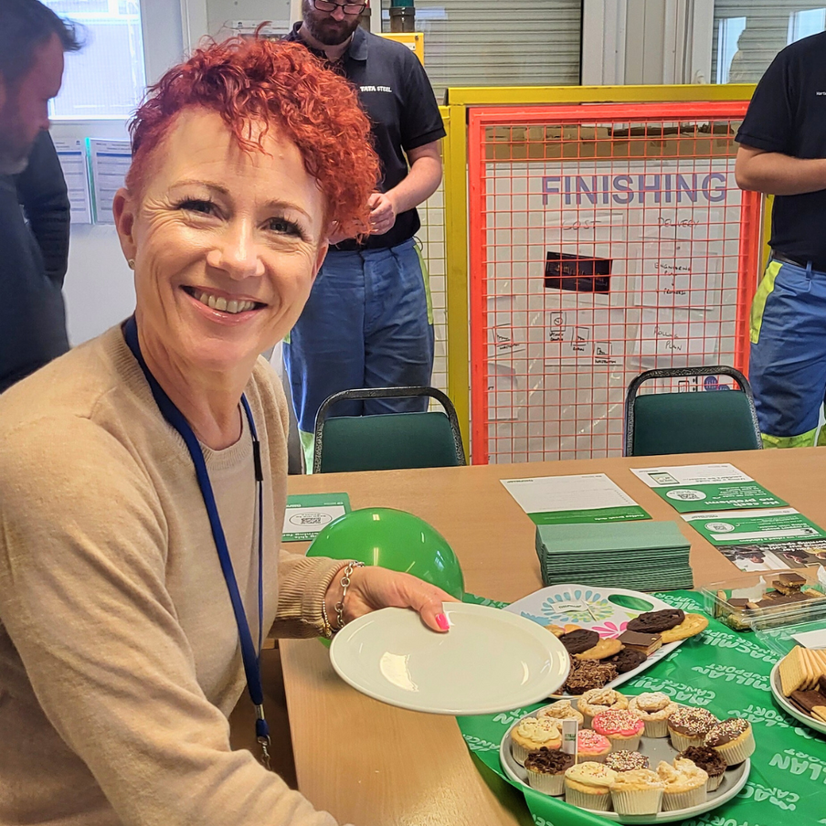 Smiling woman with red hair reaches for cake on table